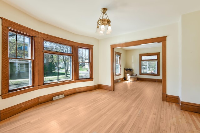 empty room featuring light wood-style floors, baseboards, and a chandelier