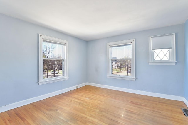 unfurnished room with baseboards, light wood-style flooring, and visible vents