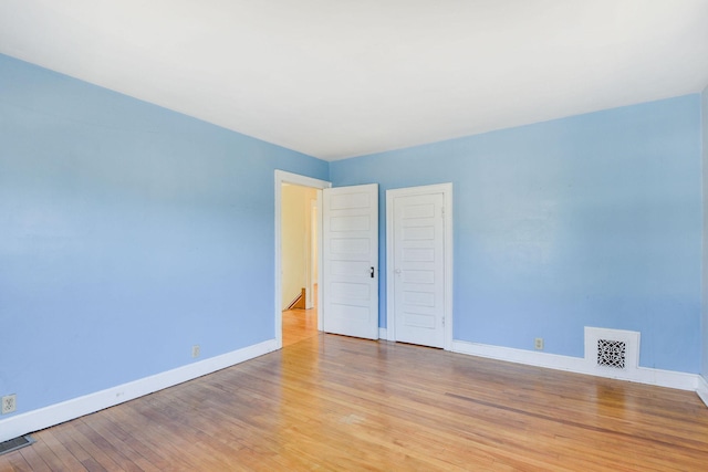 empty room featuring baseboards, visible vents, and light wood finished floors