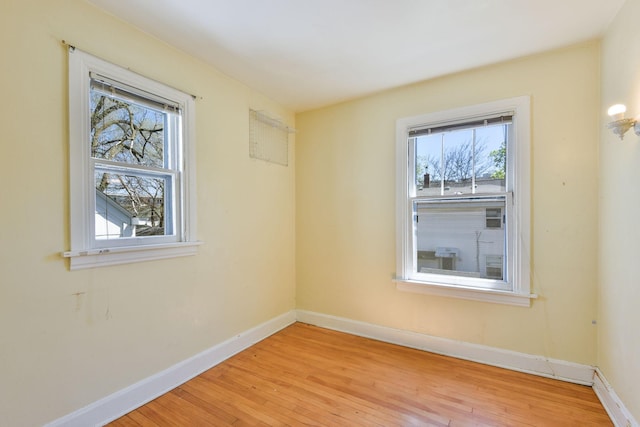 unfurnished room with baseboards, light wood-style flooring, and a wealth of natural light
