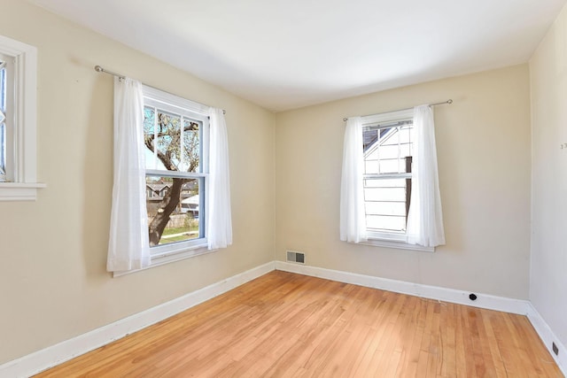 unfurnished room with baseboards, light wood-style flooring, and visible vents