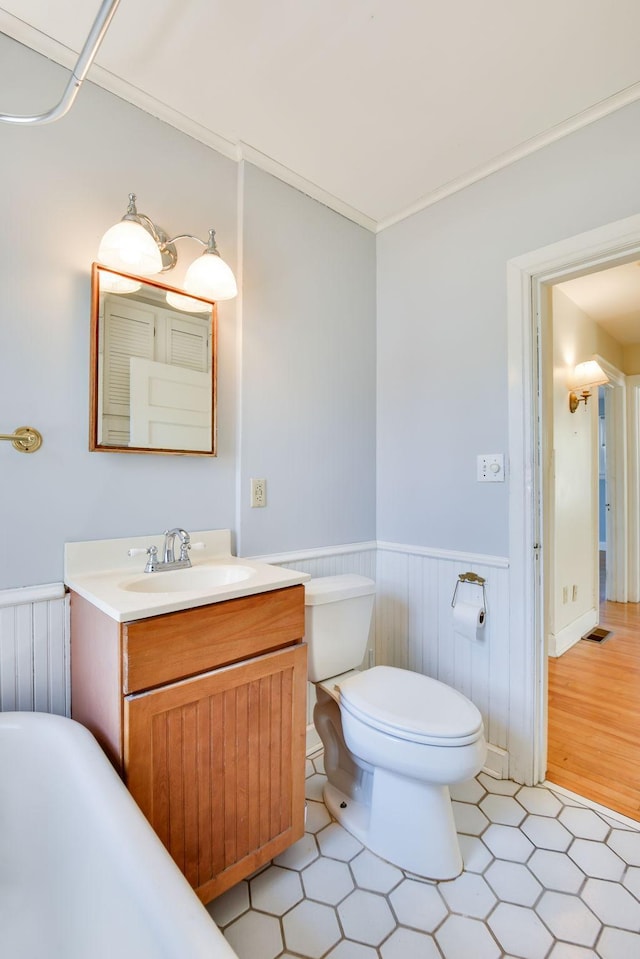 bathroom featuring vanity, crown molding, radiator, toilet, and a wainscoted wall