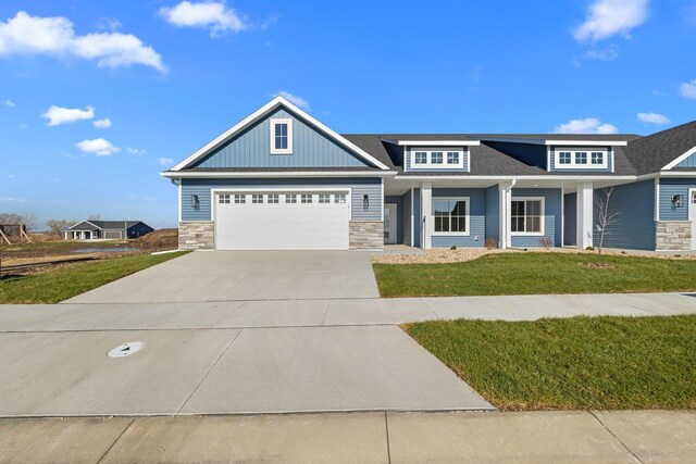 1003 11th Pl NW, Kasson, MN 55944 - view of front facade featuring stone siding, driveway, a front yard, a garage, and a shingled roof