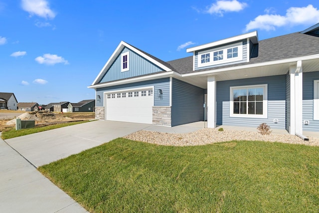 1003 11th Pl NW, Kasson, MN 55944 - craftsman-style home with driveway, a front lawn, an attached garage, stone siding, and roof with shingles