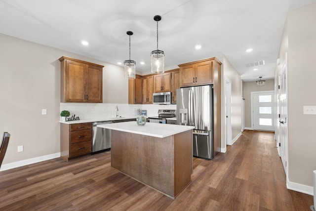 kitchen with stainless steel appliances, decorative light fixtures, dark hardwood / wood-style flooring, a center island, and decorative backsplash