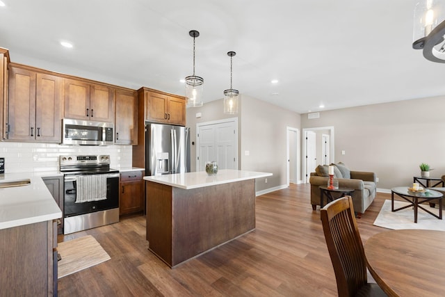 kitchen featuring pendant lighting, appliances with stainless steel finishes, dark wood-type flooring, and tasteful backsplash