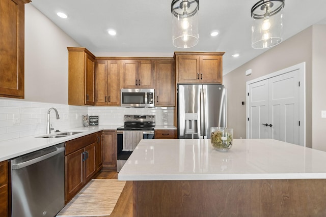 kitchen featuring tasteful backsplash, stainless steel appliances, hanging light fixtures, sink, and a center island