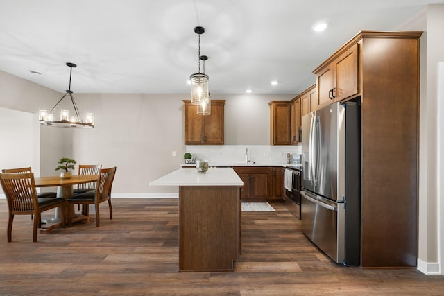 kitchen featuring stainless steel appliances, decorative backsplash, dark hardwood / wood-style floors, a kitchen island, and pendant lighting