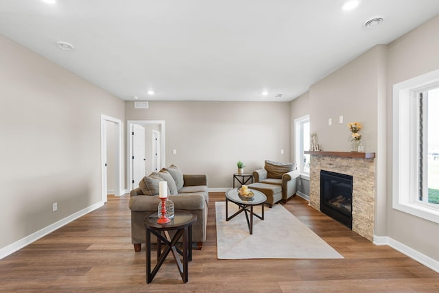 living room featuring a stone fireplace and hardwood / wood-style flooring