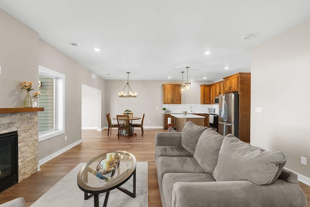 living room with a fireplace, light hardwood / wood-style flooring, and a notable chandelier