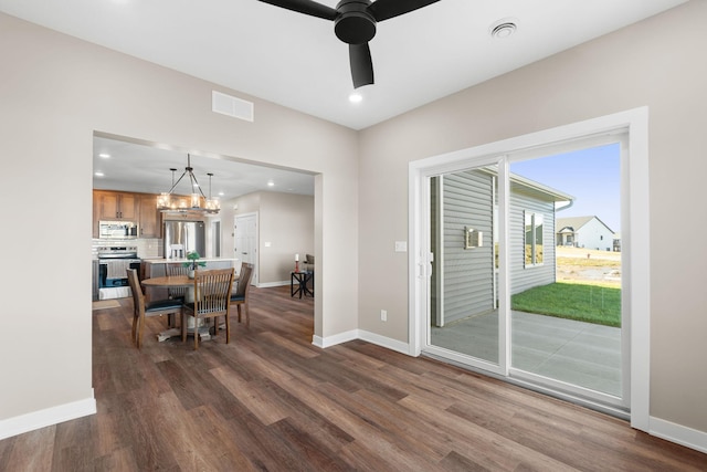 dining space featuring dark hardwood / wood-style floors and ceiling fan with notable chandelier