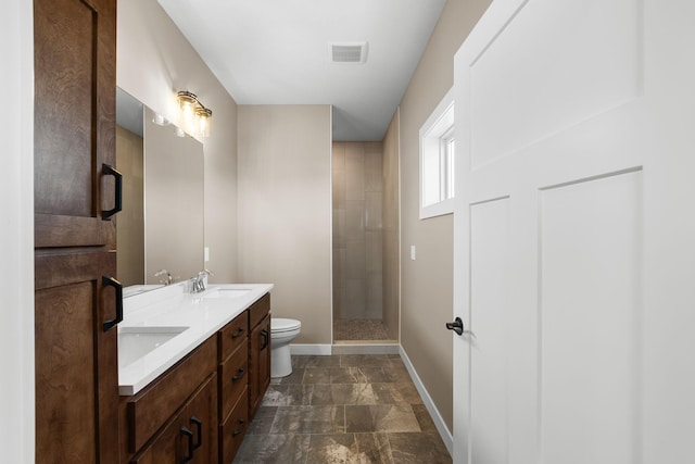 bathroom with toilet, vanity, and tiled shower