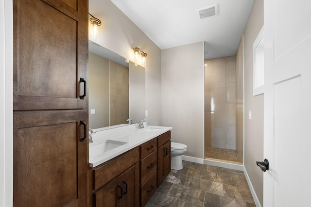 bathroom featuring tiled shower, toilet, and vanity