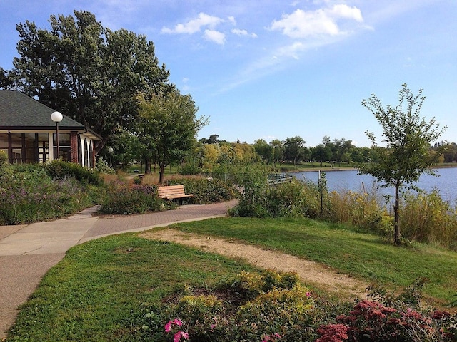 view of yard featuring a sunroom and a water view