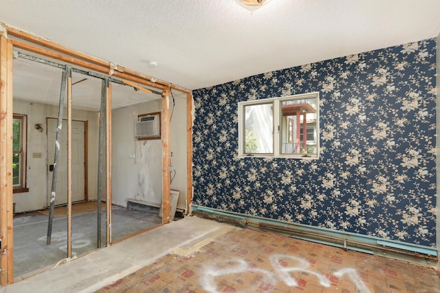 unfurnished bedroom with a wall unit AC, a closet, and a textured ceiling