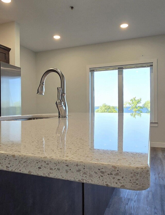 kitchen with dark hardwood / wood-style floors, light stone countertops, and sink