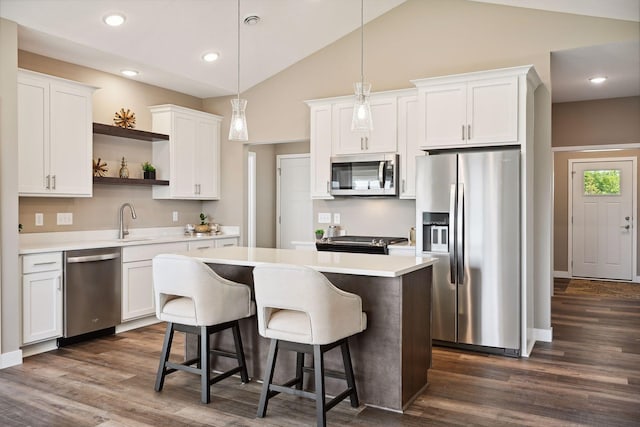 kitchen featuring white cabinets, a center island, stainless steel appliances, dark wood-type flooring, and pendant lighting