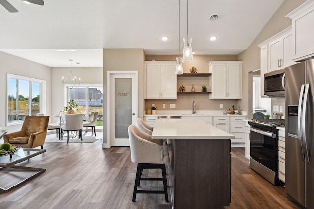 kitchen with a center island, stainless steel appliances, white cabinetry, sink, and dark wood-type flooring