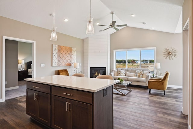 kitchen with a large fireplace, a center island, ceiling fan, dark wood-type flooring, and dark brown cabinetry