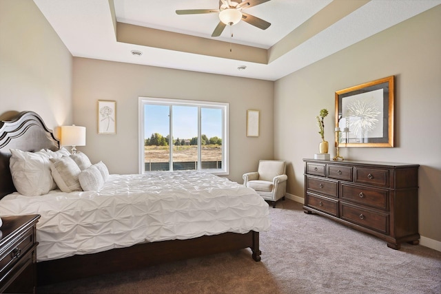 bedroom with a tray ceiling, light colored carpet, and ceiling fan