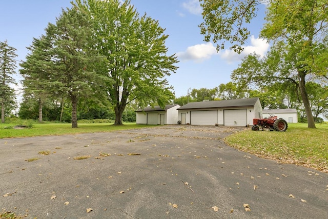 view of front facade with a garage, an outdoor structure, and a front lawn