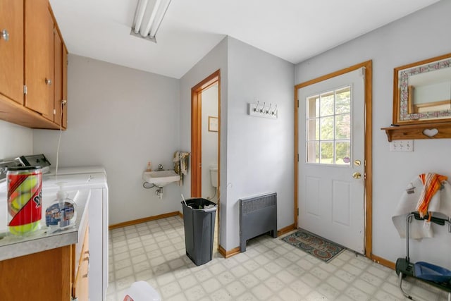 clothes washing area with washing machine and dryer, sink, radiator heating unit, and cabinets