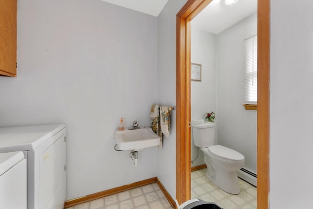 bathroom with separate washer and dryer, toilet, sink, and a baseboard heating unit