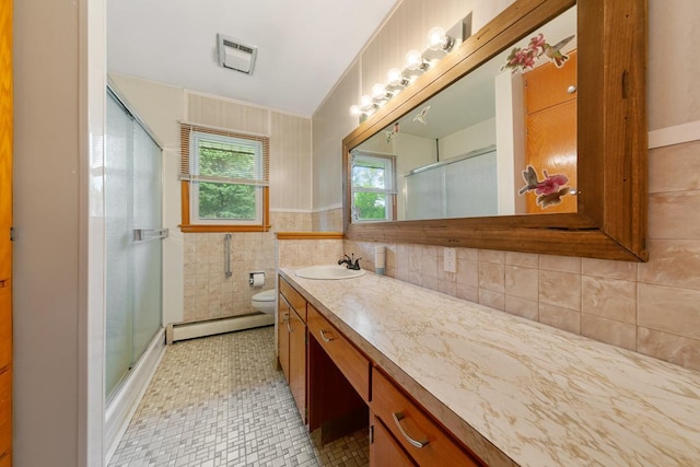 bathroom with toilet, an enclosed shower, tile walls, a baseboard heating unit, and vanity