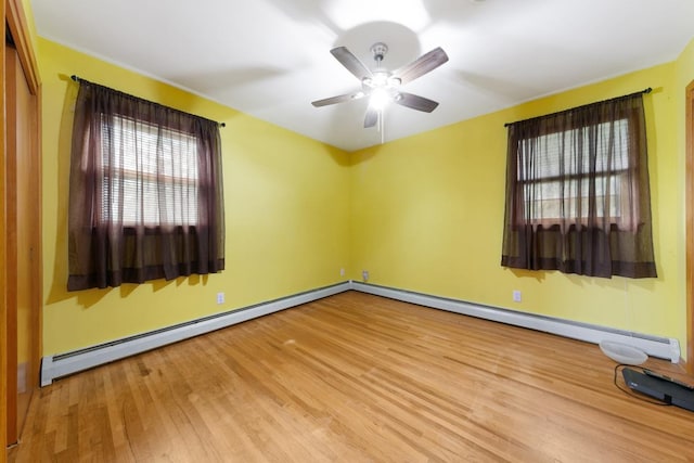 empty room featuring baseboard heating, hardwood / wood-style flooring, and ceiling fan