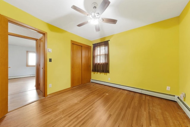 unfurnished bedroom featuring ceiling fan, a baseboard radiator, a closet, and light hardwood / wood-style floors