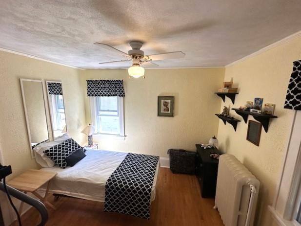 bedroom with dark hardwood / wood-style floors, ornamental molding, ceiling fan, and radiator heating unit