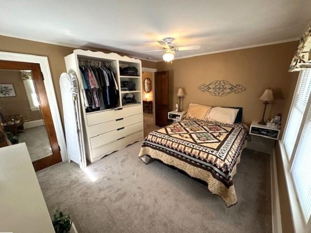 carpeted bedroom with a closet, ceiling fan, and crown molding