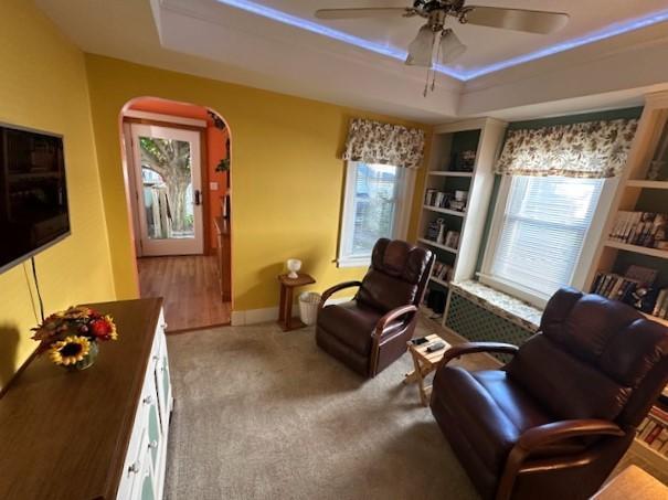 sitting room featuring ceiling fan, a tray ceiling, and carpet flooring