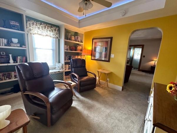 207 6th St, Montevideo, MN 56265 - living area featuring arched walkways, ceiling fan, carpet floors, and a tray ceiling