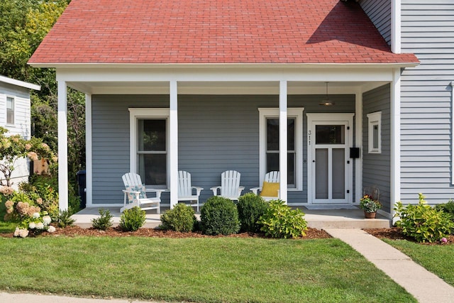 doorway to property with a yard and covered porch