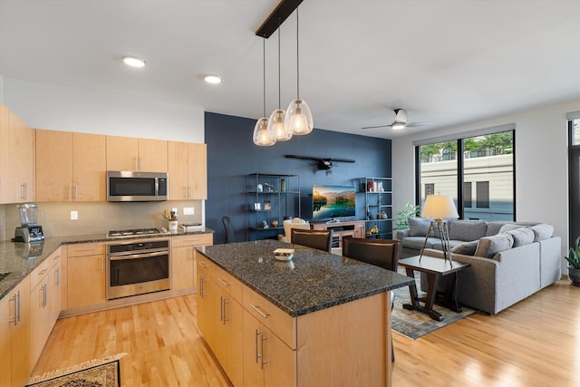 kitchen featuring a center island, light wood-type flooring, ceiling fan with notable chandelier, stainless steel appliances, and light brown cabinets