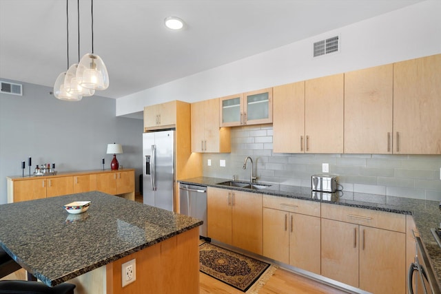 kitchen featuring a center island, light wood-type flooring, appliances with stainless steel finishes, sink, and light brown cabinets