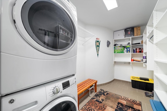 clothes washing area featuring light tile patterned floors and stacked washer / dryer