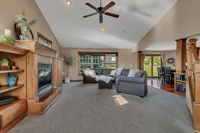 living room featuring a tiled fireplace, high vaulted ceiling, ornate columns, dark wood-type flooring, and ceiling fan