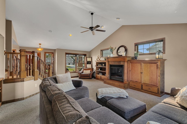 living area featuring stairs, a healthy amount of sunlight, a glass covered fireplace, and light colored carpet