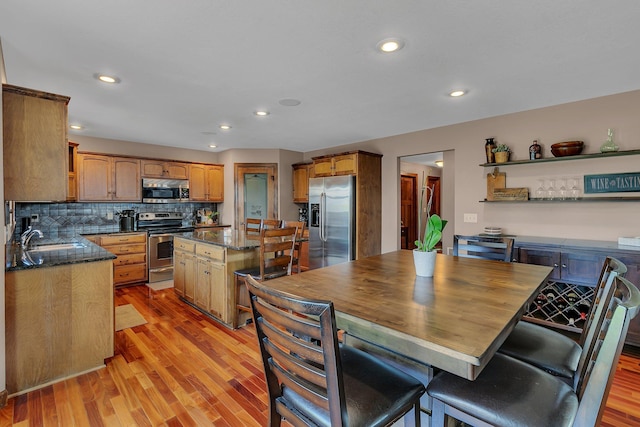 kitchen with stainless steel appliances, a kitchen island, open shelves, and light wood-style flooring