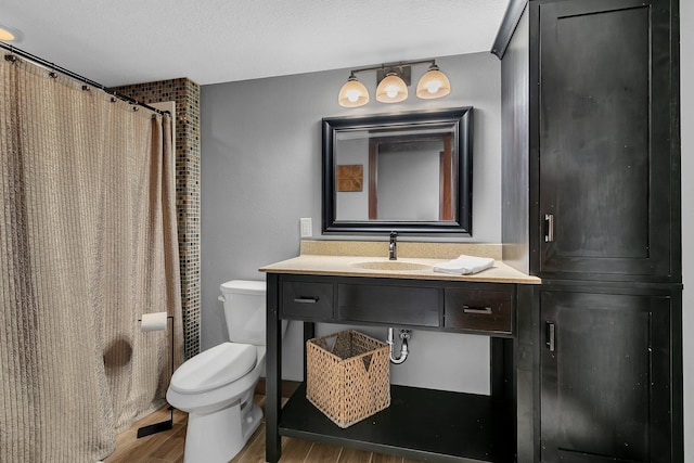 bathroom featuring a shower with shower curtain, toilet, wood finished floors, a textured ceiling, and vanity