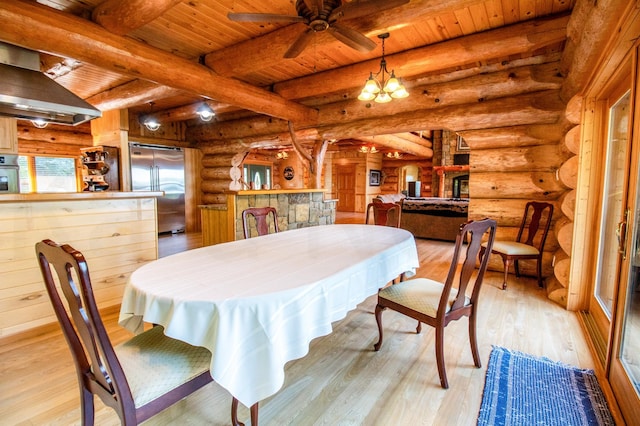 dining room with ceiling fan with notable chandelier, beamed ceiling, light hardwood / wood-style floors, rustic walls, and wooden ceiling