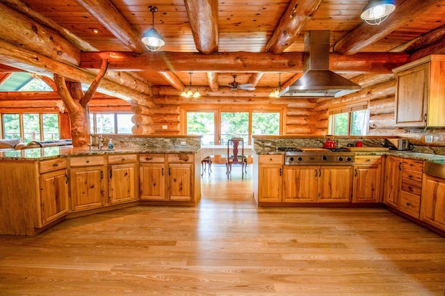 kitchen with pendant lighting, stainless steel gas cooktop, rustic walls, and kitchen peninsula