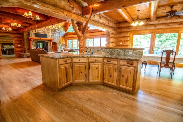 kitchen with light stone countertops, pendant lighting, log walls, light hardwood / wood-style floors, and wooden ceiling