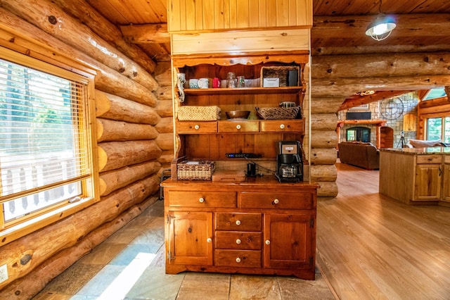 office area featuring beam ceiling, a wealth of natural light, rustic walls, and wooden ceiling