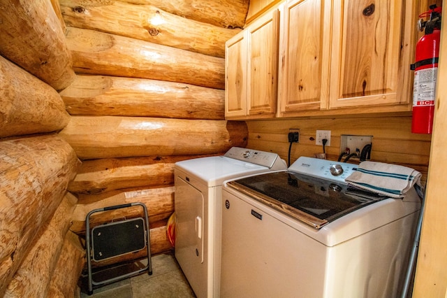 clothes washing area with cabinets, rustic walls, and independent washer and dryer