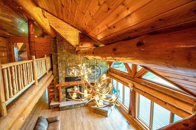 unfurnished living room featuring vaulted ceiling, a notable chandelier, wood-type flooring, a stone fireplace, and wooden ceiling