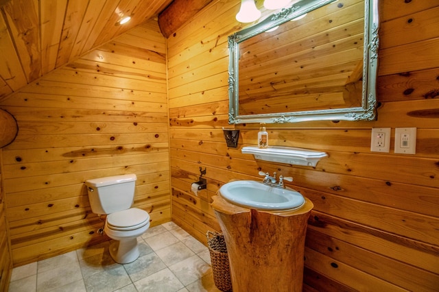 bathroom with toilet, wooden walls, wooden ceiling, tile patterned flooring, and sink