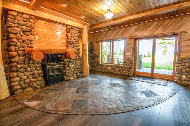 unfurnished living room featuring wood walls, a wood stove, beam ceiling, and wood ceiling